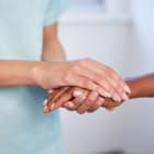 Close up of nurse holding patient’s hand during difficult diagnosis, counselling